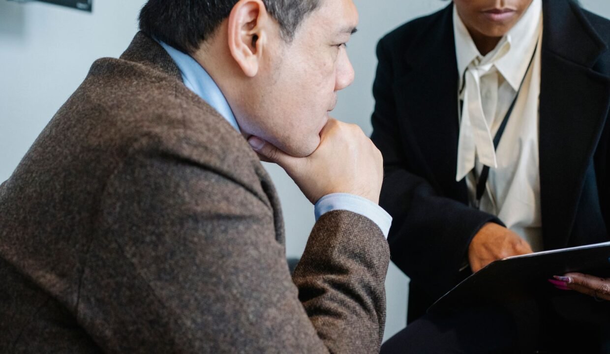 Colleagues in formal suits reviewing documents together in a modern office
