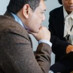 Colleagues in formal suits reviewing documents together in a modern office